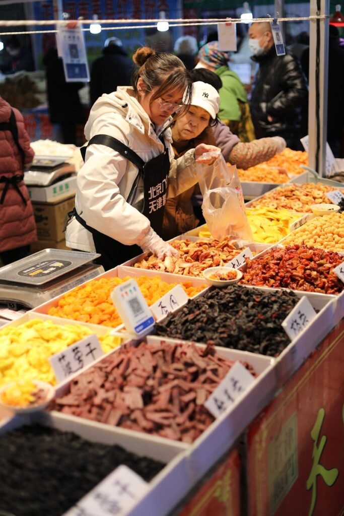 Vendors sell dried fruits and nuts at a market.