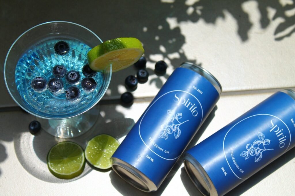 two cans of blueberry limeade next to a glass of blueberry limeade