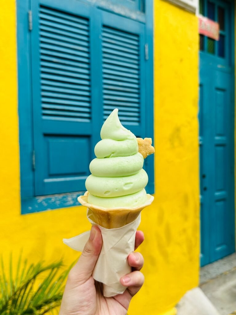 a person holding up a green ice cream cone